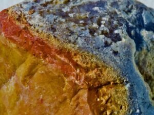 Macro shot of a volcanic mineral with red, orange and blue colouration